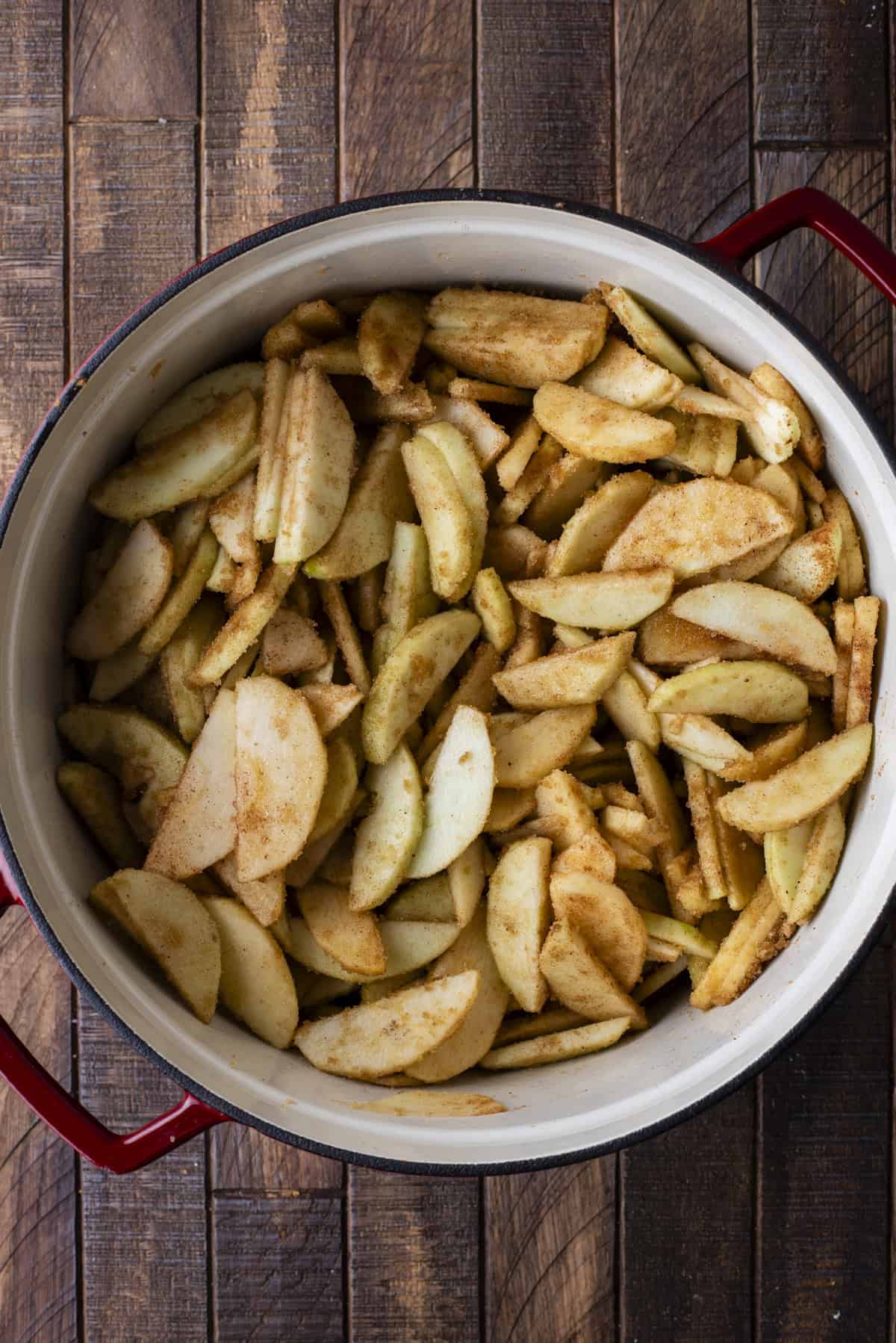 over head view of cooked apples in a large pot on a wooden surface