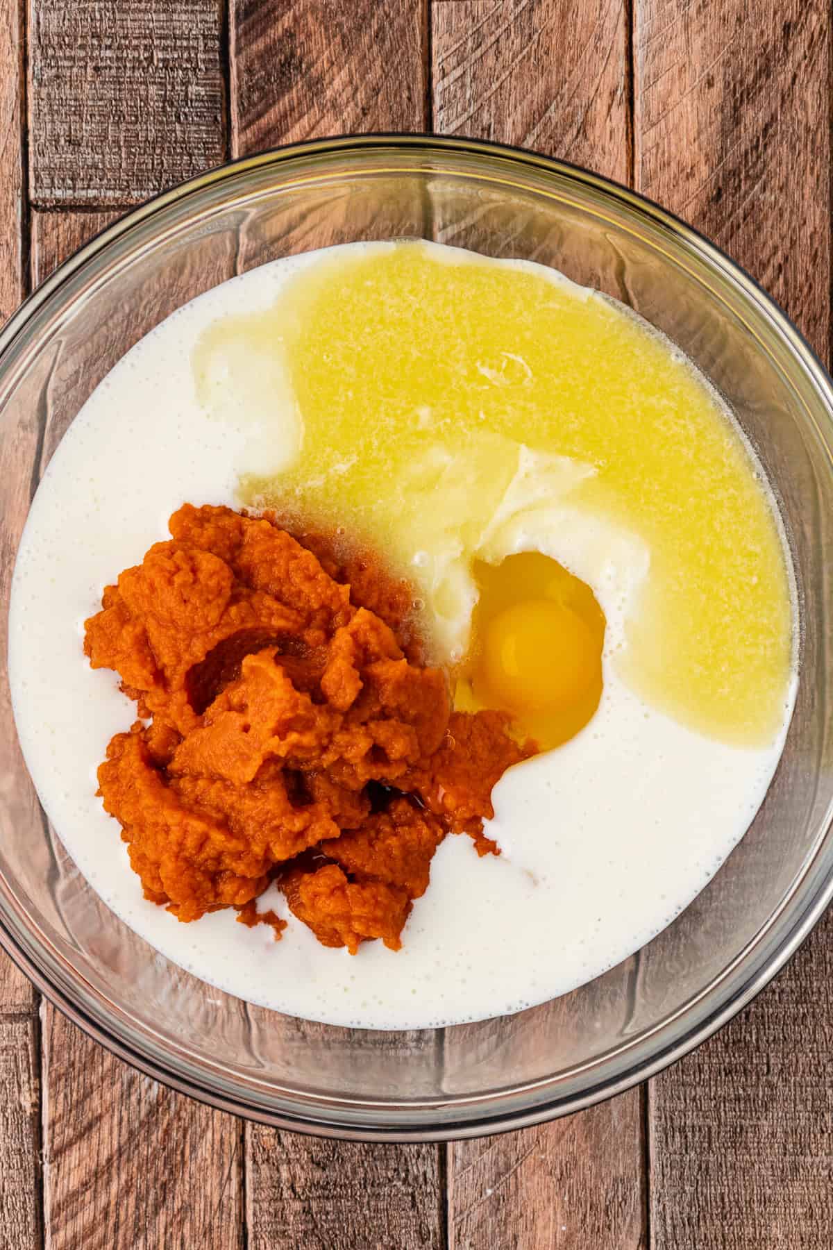 milk, egg, and pumpkin puree in a large clear glass bowl