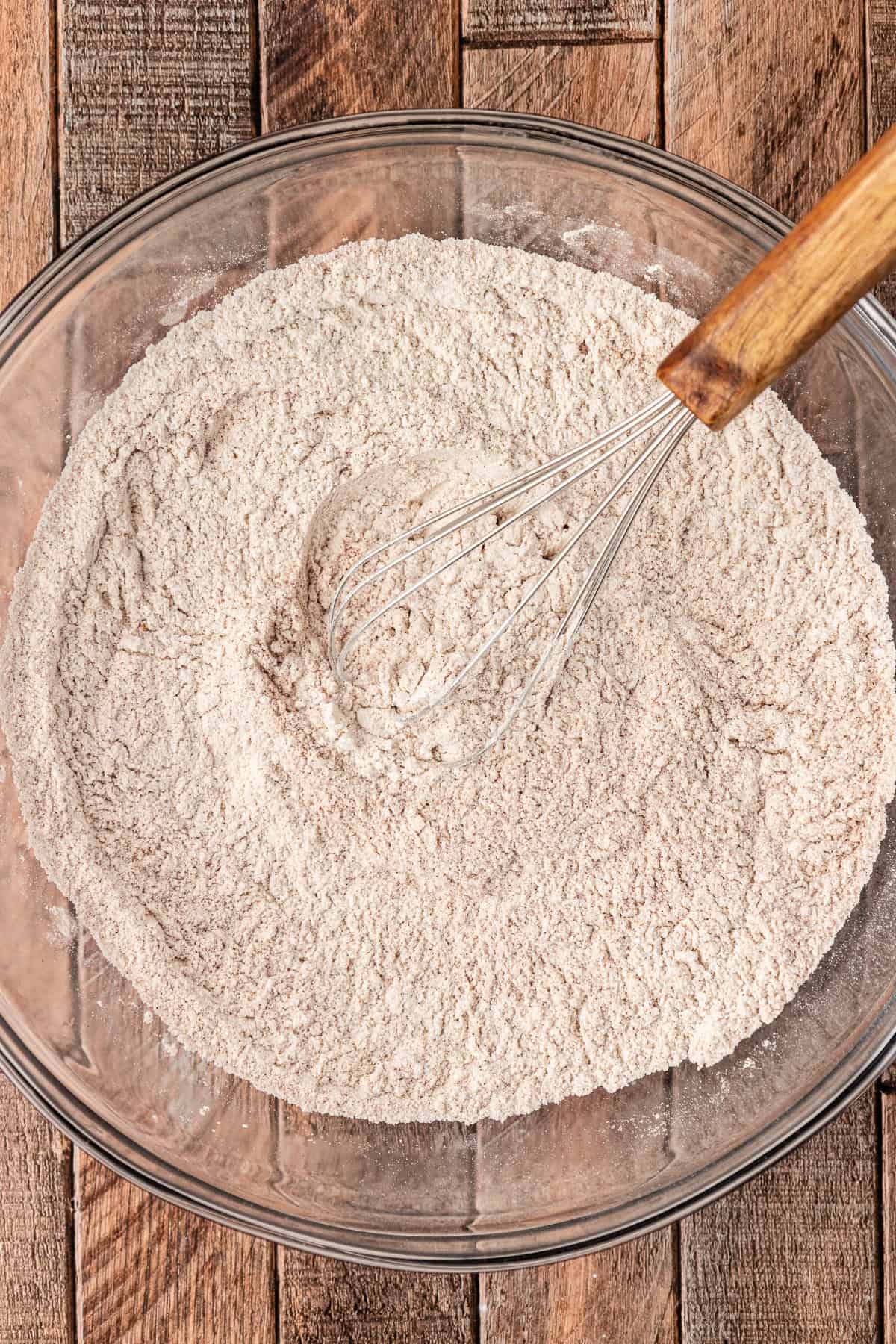 a flour mixture in a large glass bowl with a whisk