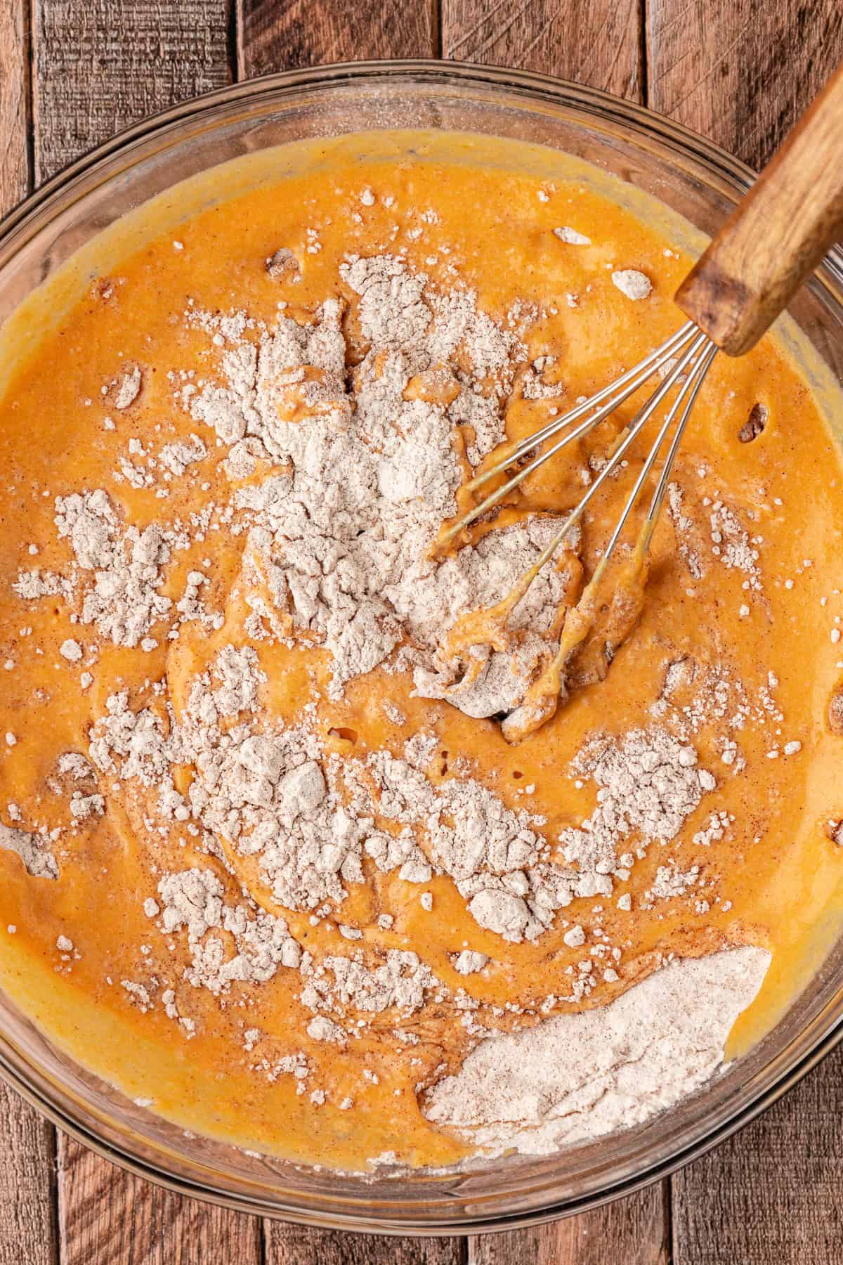 pumpkin pancake batter being mixed in a large glass bowl with a whisk