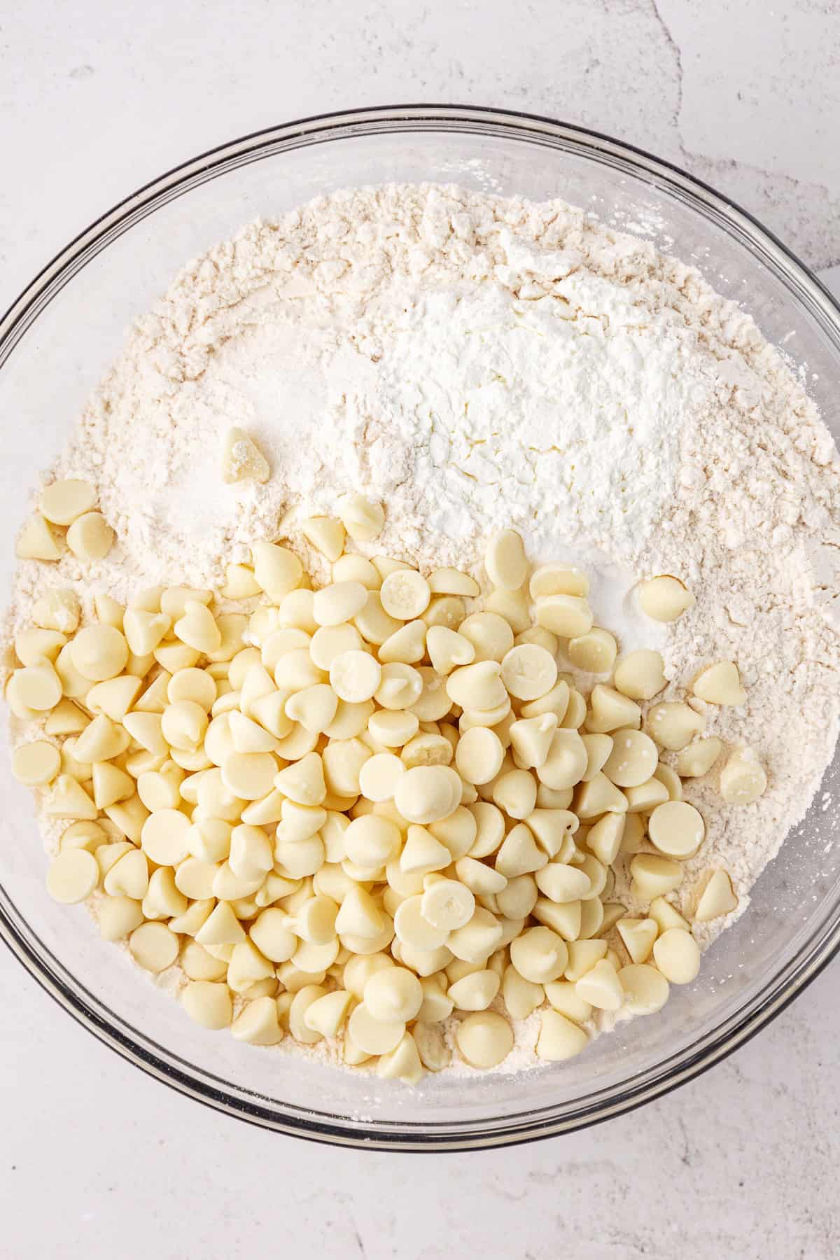 white chocolate chips and a flour mixture in a large glass bowl