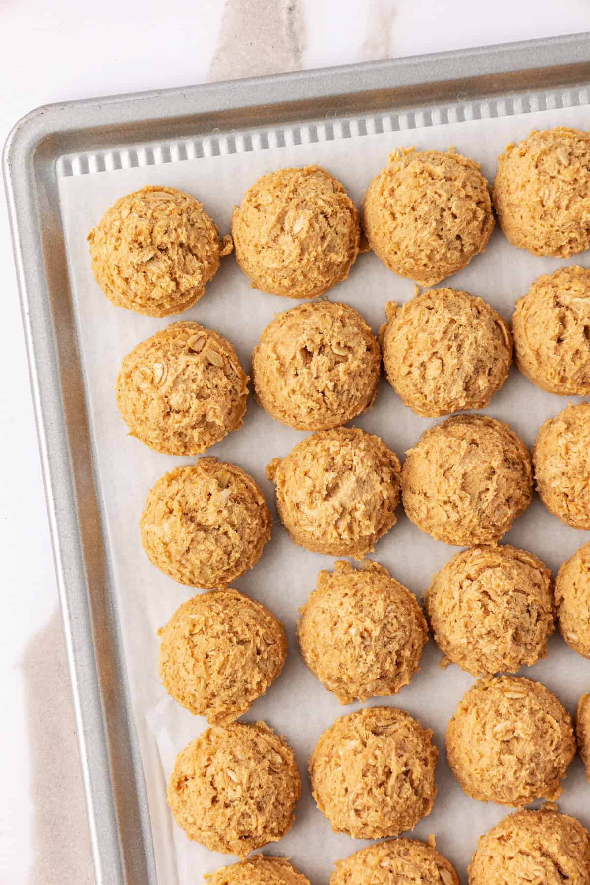 peanut butter oatmeal cookie dough balls on a baking sheet lined with parchment paper