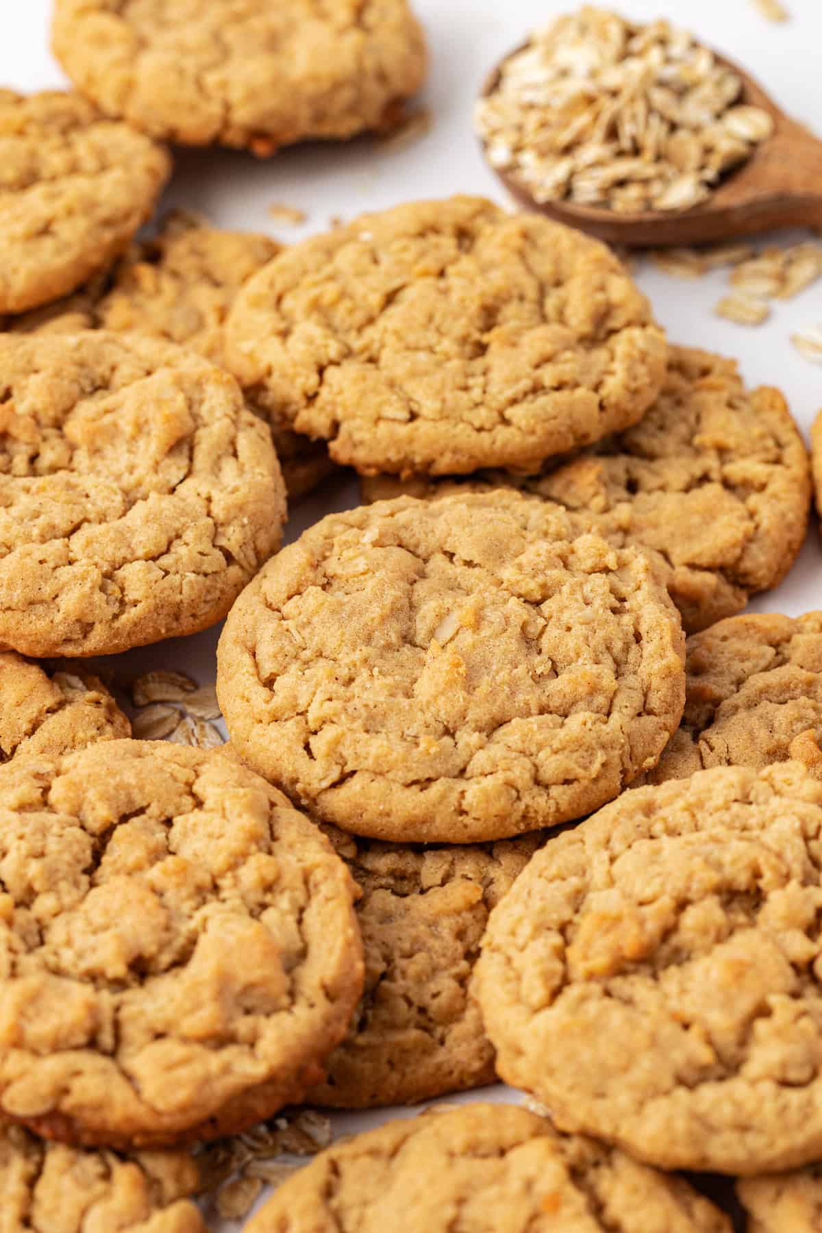 peanut butter oatmeal cookies scattered and stacked with oats scattered around