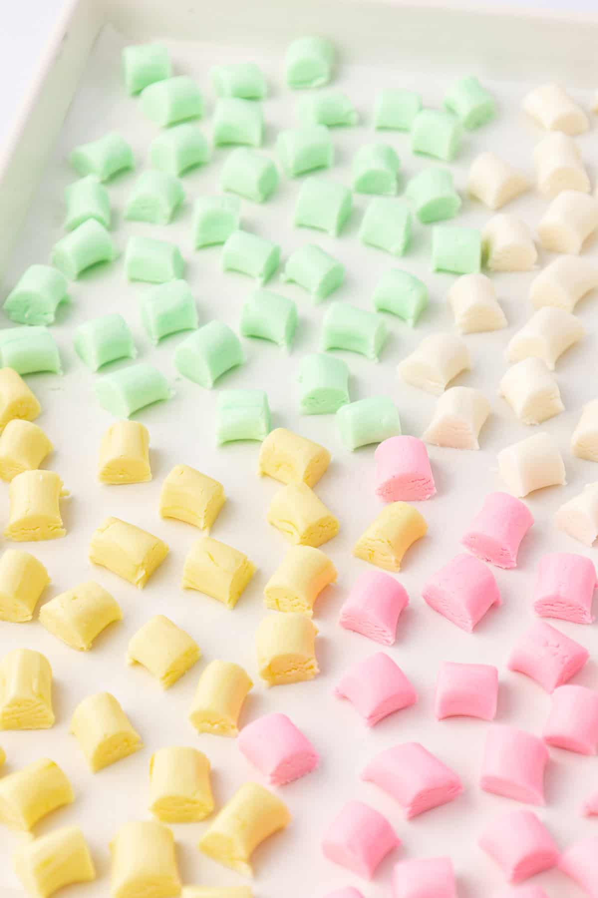 sheet pan with yellow, green, white and pink butter mints arranged in one layer on the pan