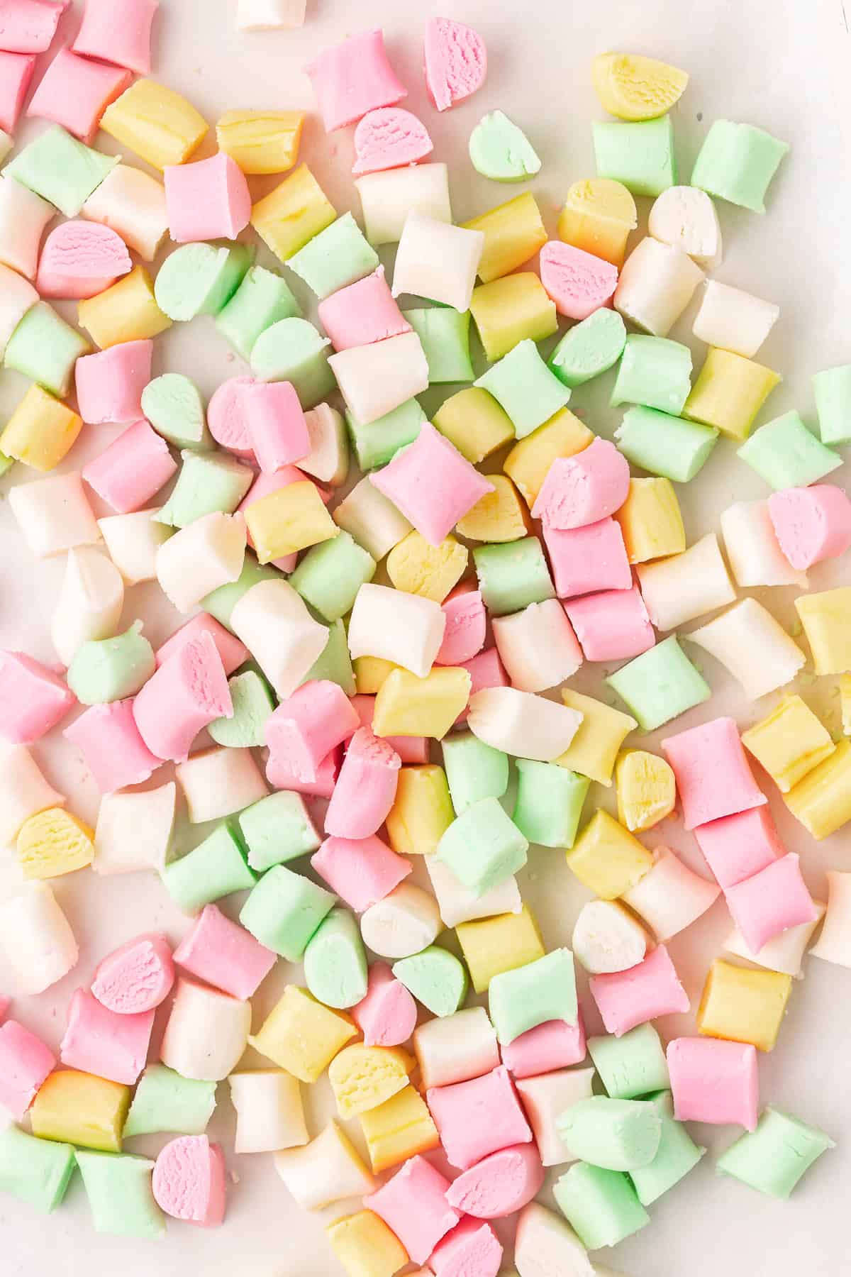 over head view of a large pile and scattered pink, yellow, green, and white butter mints