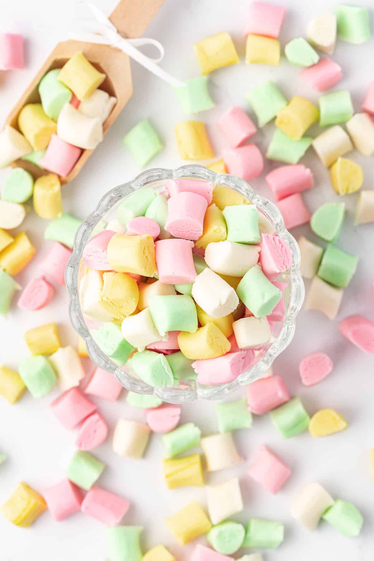 overhead view of a small glass dish full of butter mints with more mints scattered around