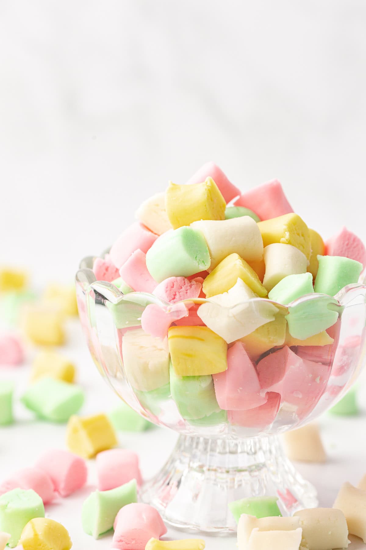 glass trifle dish full of white, green, pink and yellow butter mints with more mints scattered around