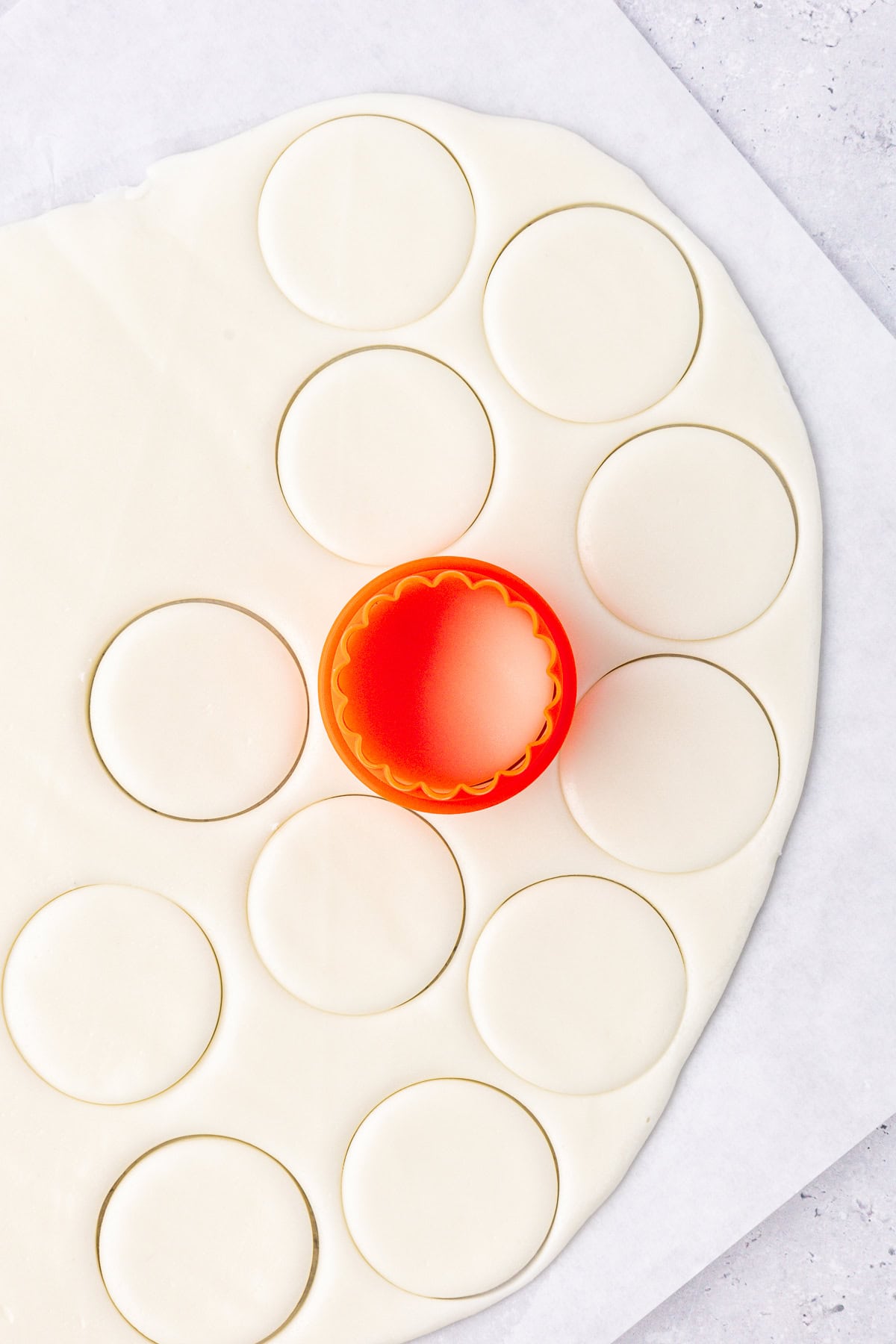 peppermint patty filling rolled out flat on white parchment paper and being cut into round discs with a cookie cutter