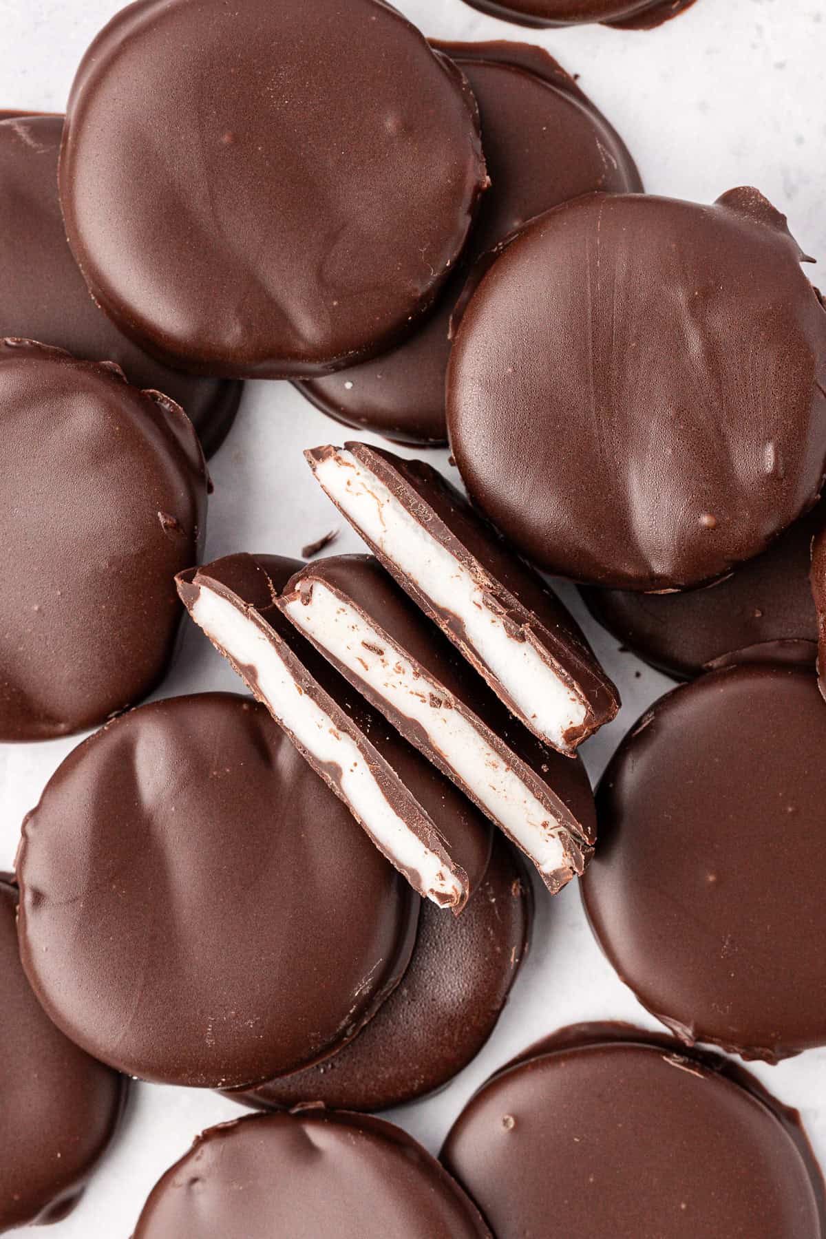 scattered and stacked peppermint patties with three halves in the middle on their sides, showing the white peppermint filling