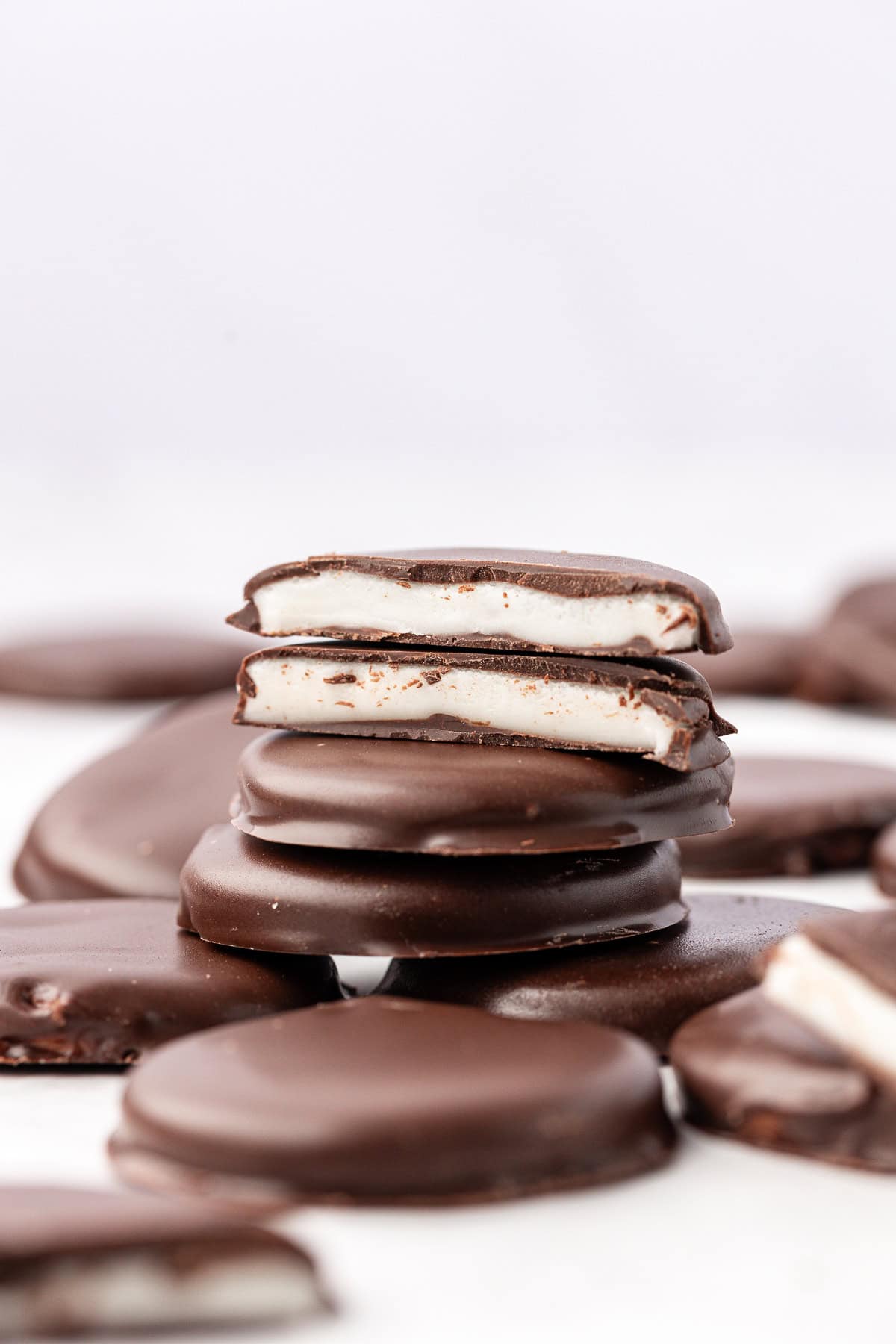 scattered and stacked peppermint patties, with two halves on top of the stack showing the white inside