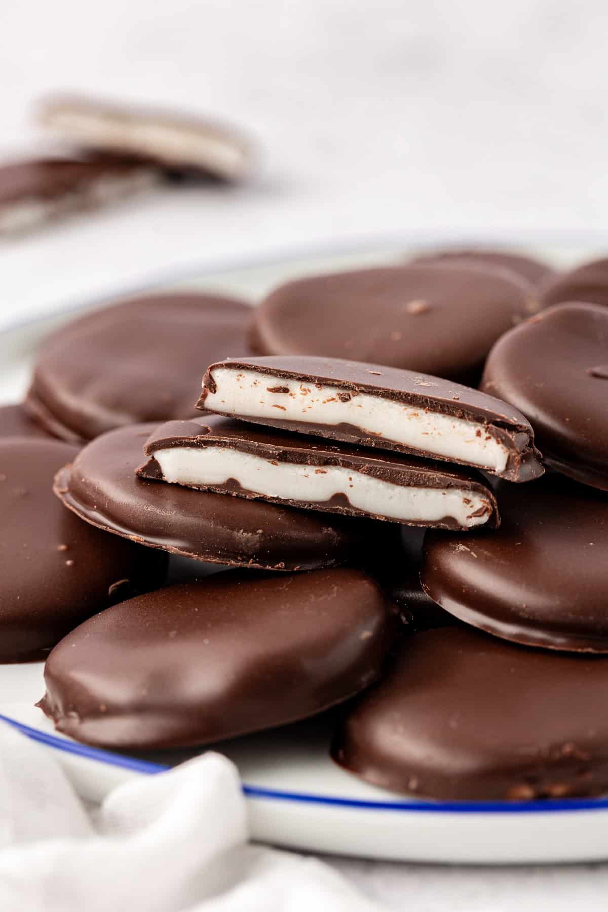 a plate filled with peppermint patties with one cut in half on top showing the white filling inside