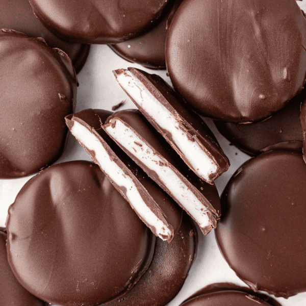 scattered and stacked peppermint patties with three halves in the middle on their sides, showing the white peppermint filling