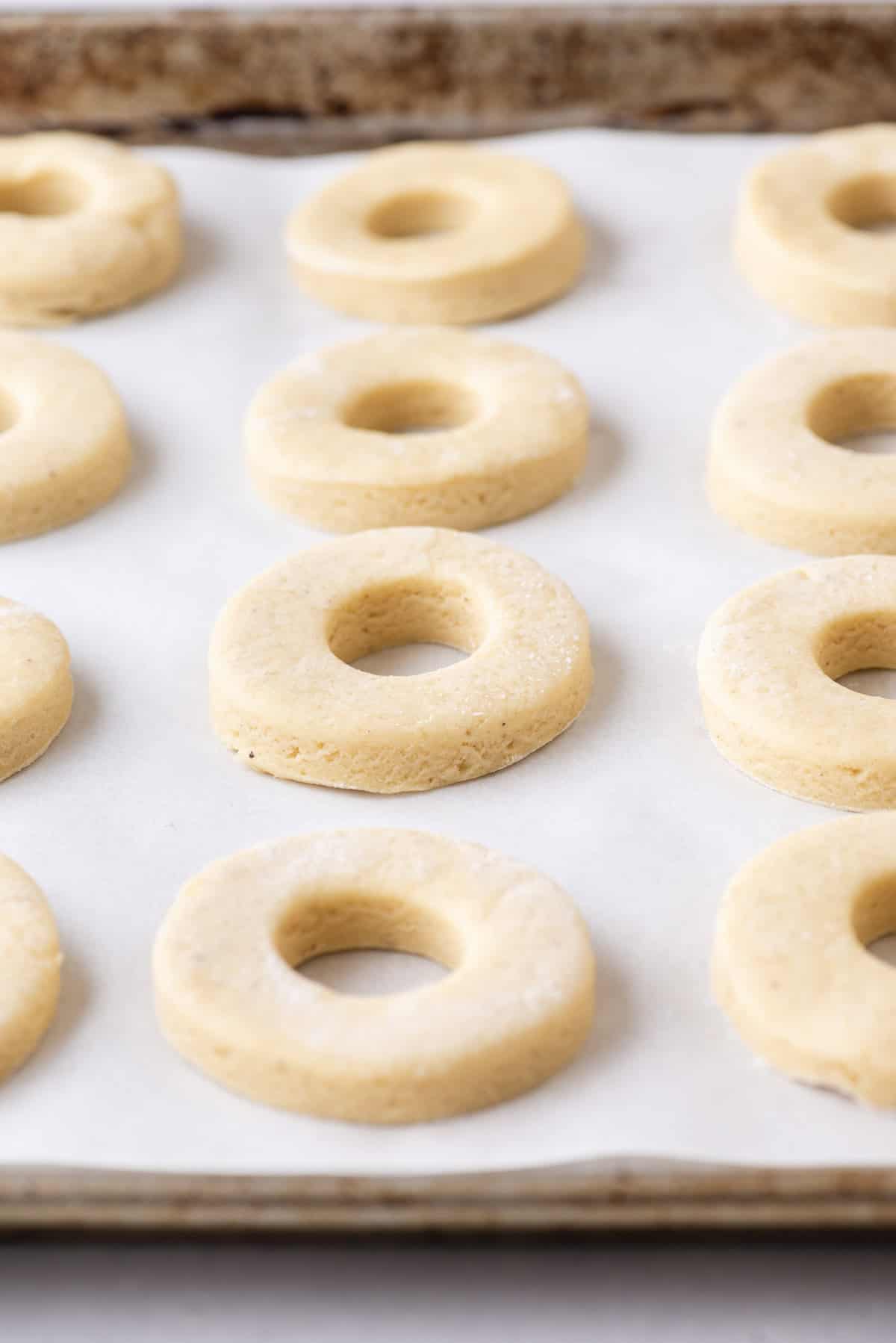 cake donut dough in rows on a baking sheet lined with parchment paper