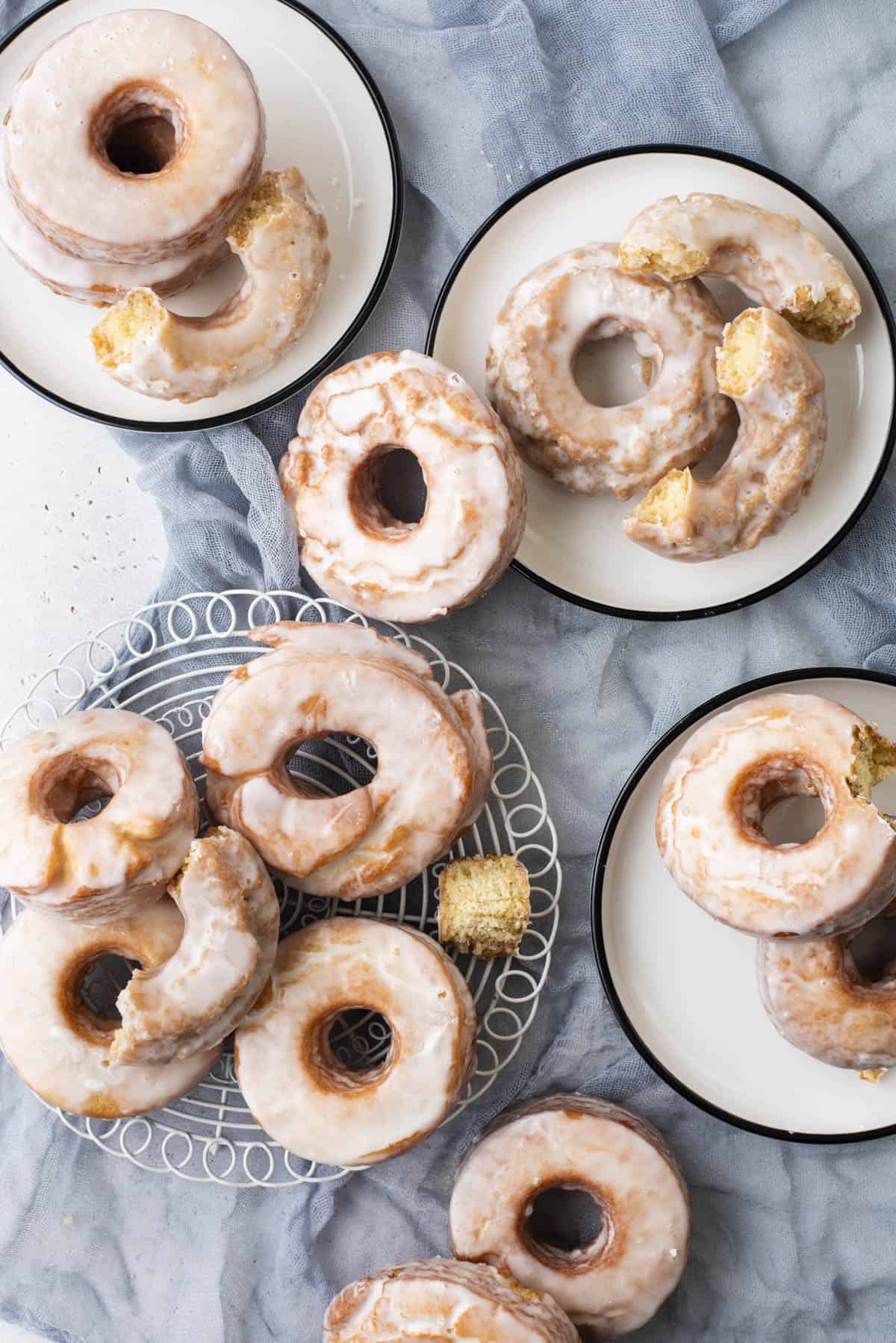 over head view of several small plates of glazed old fashioned donuts stacked and piled on them