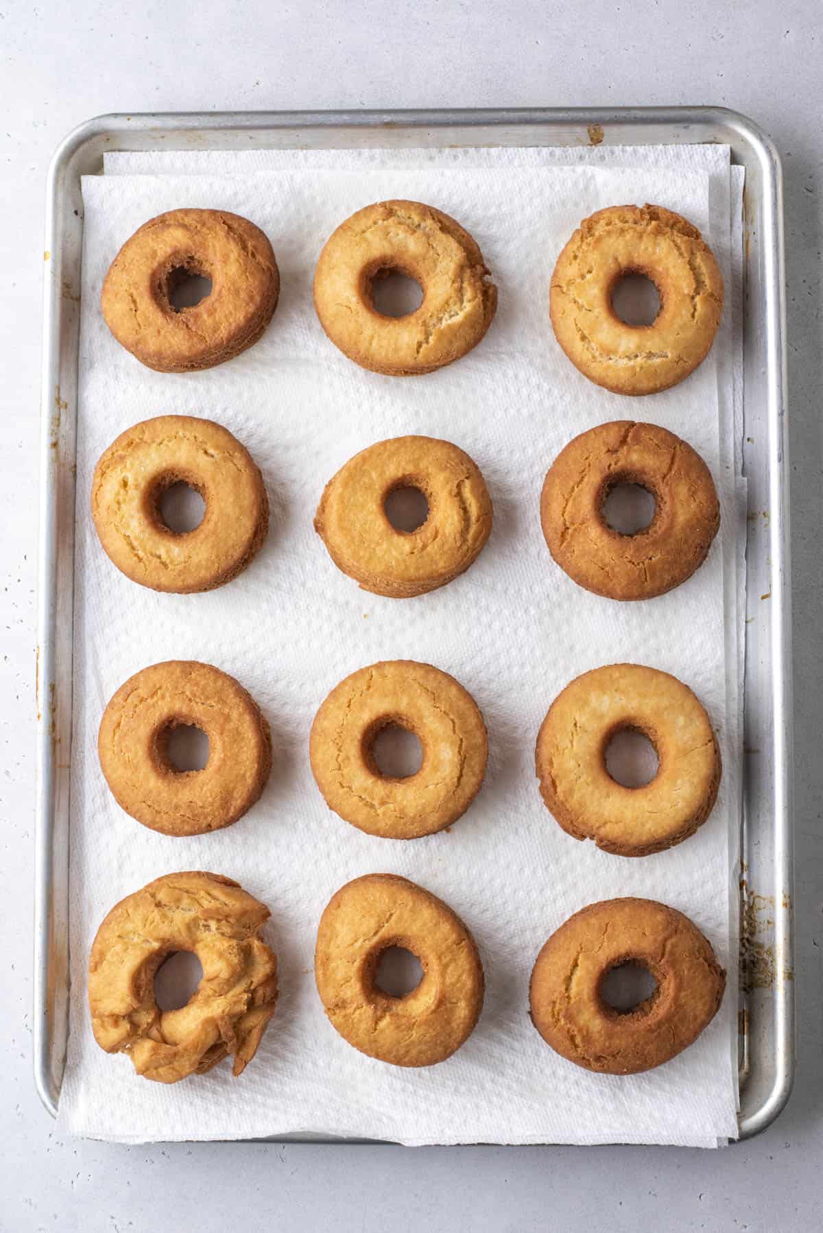 old fashioned donuts cooling on a baking sheet lined with paper towels