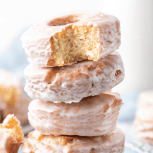 a stack of old fashioned donuts with a bite missing out of the top donut