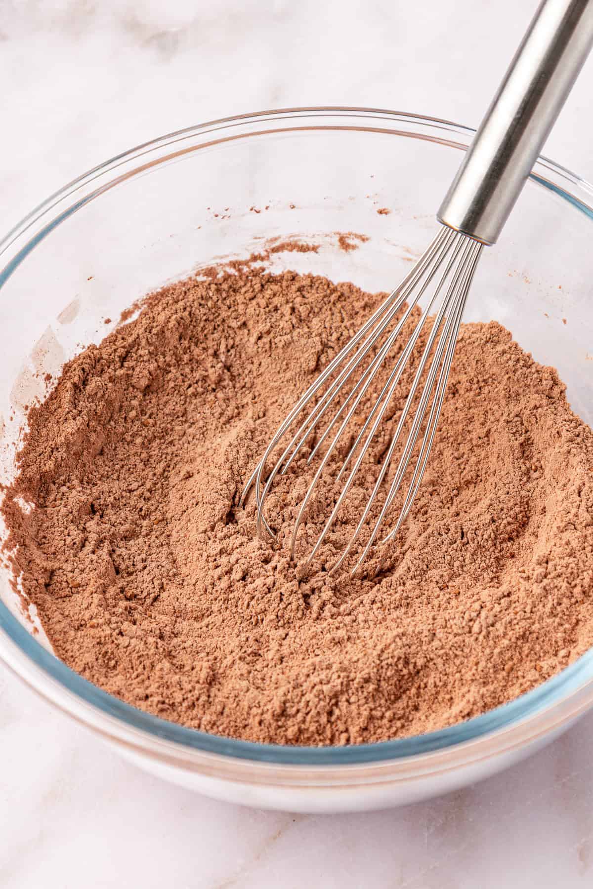 dry ingredients in a clear glass mixing bowl with a whisk