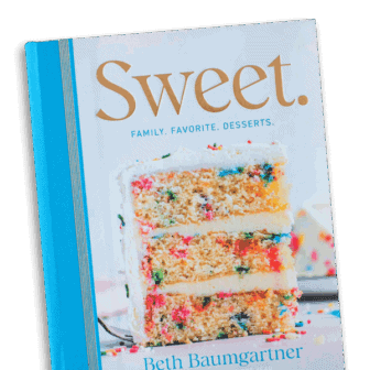 The cover of a cookbook titled Sweet. Family. Favorite. Desserts. by Beth Baumgartner, featuring a large slice of colorful funfetti layer cake with white frosting and sprinkles.