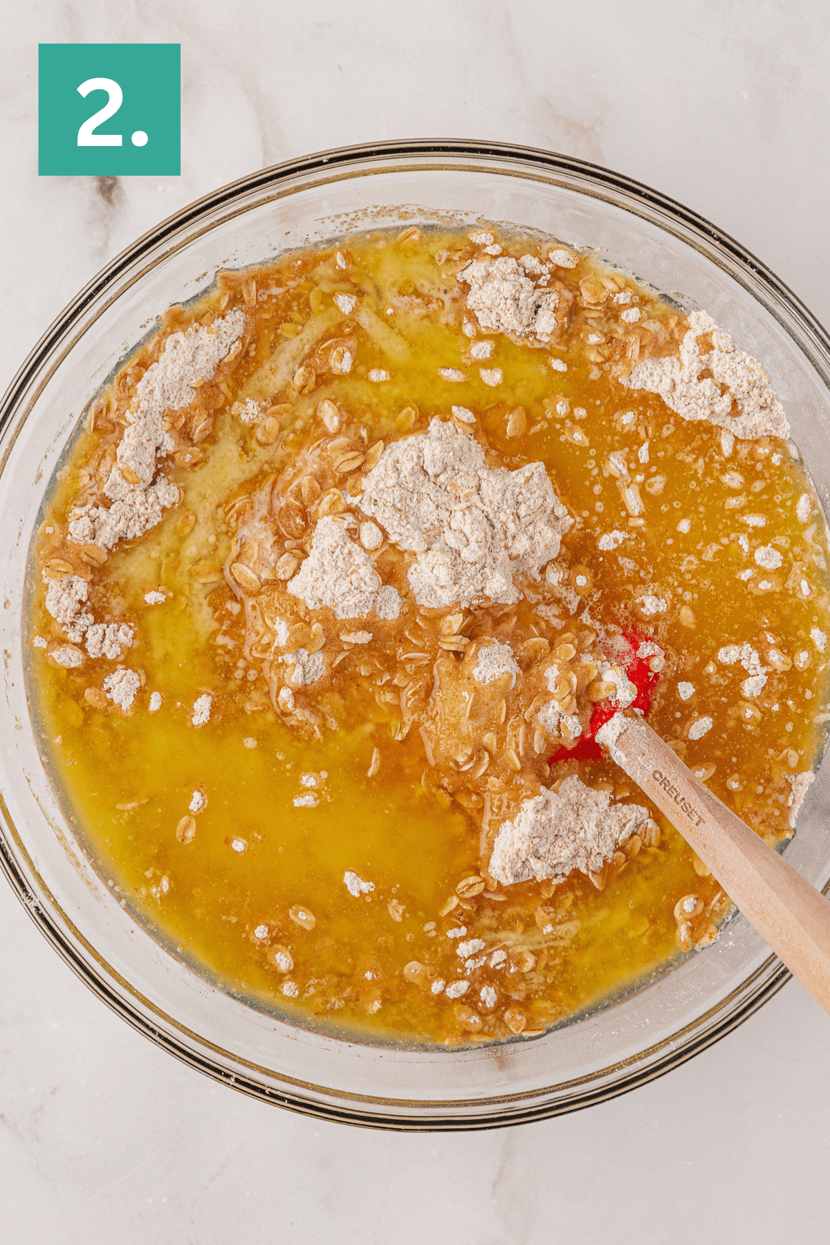 melted butter on top of a oat and flour mixture in a large glass bowl