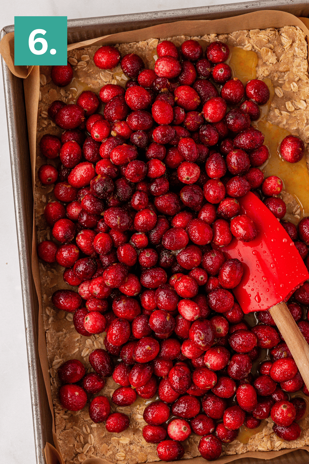 overhead view of a 9x13 pan with a oat and crumb crust pressed into the bottom and sugar coated cranberries on top