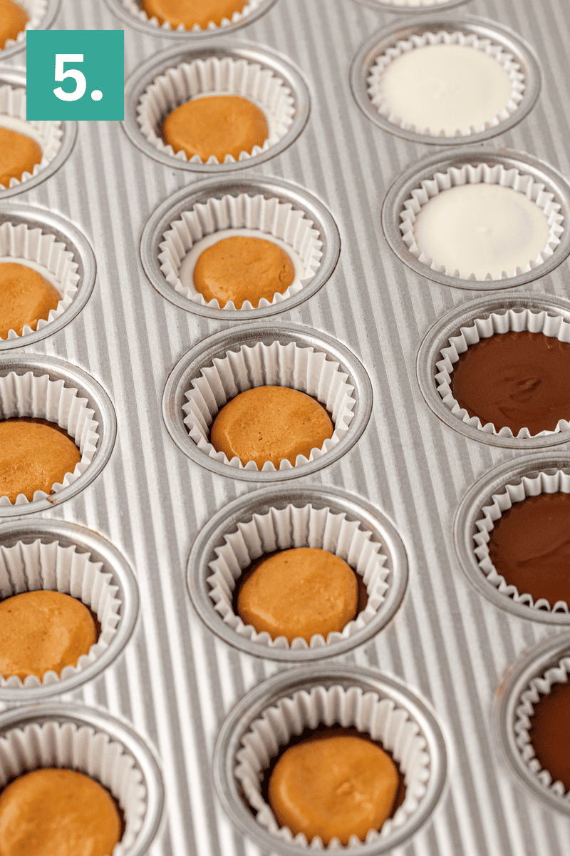 A metal muffin tin holds paper liners filled with cookie dough, chocolate, and white batter. A green box labeled 5. is in the top left corner, indicating a step in a recipe process.