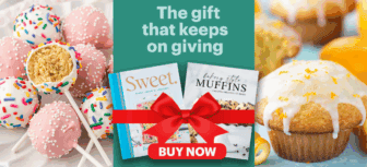 Image shows pink sprinkle cake pops, two baking books with a red bow, and lemon-glazed muffins. Text reads The gift that keeps on giving and a red BUY NOW button is below the books.