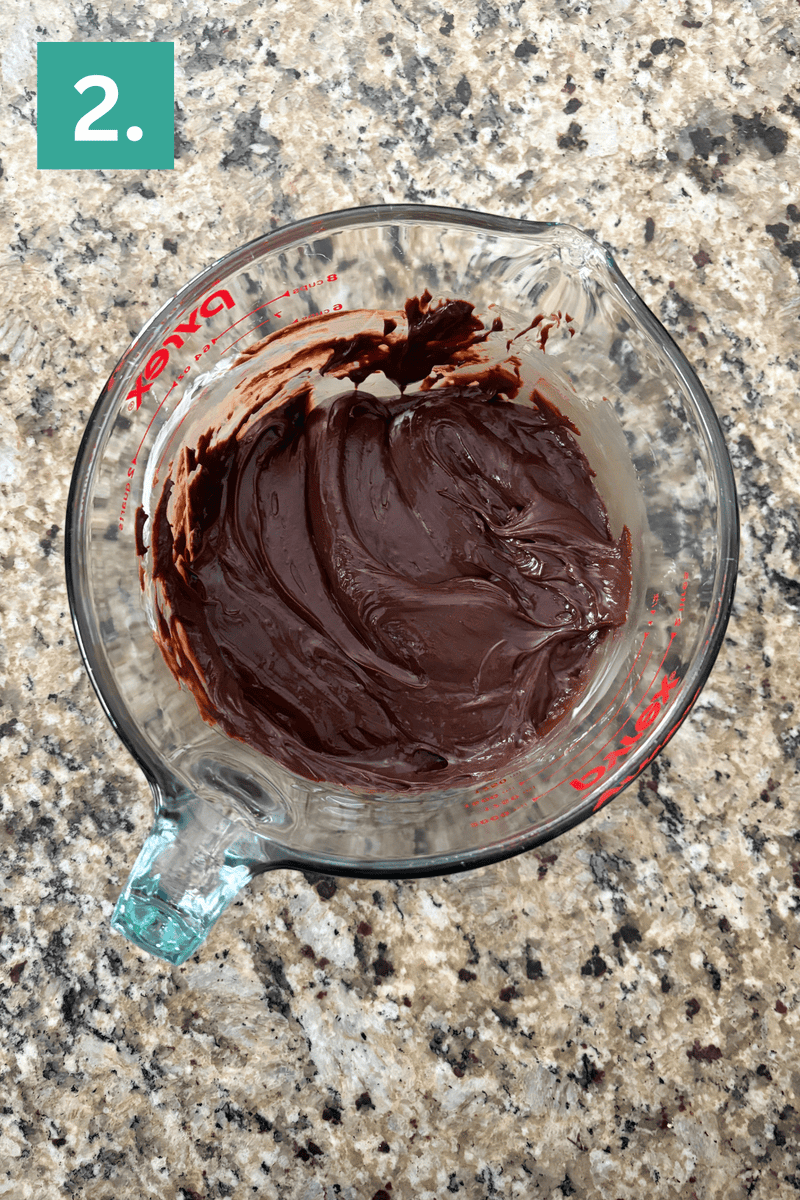A glass bowl of chocolate frosting.
