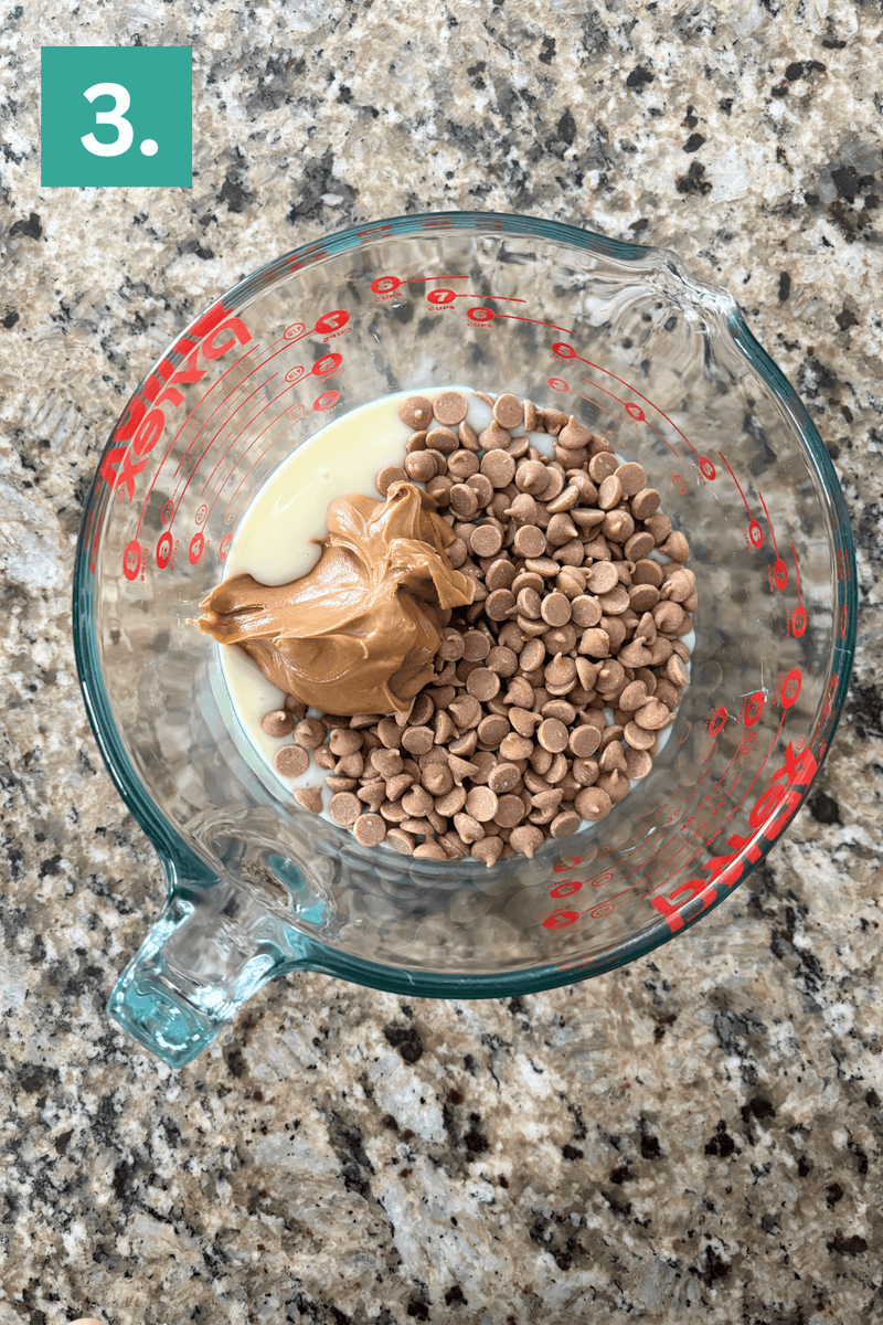 A glass measuring cup filled with peanut butter, chocolate chips, and sweetened condensed milk sits on a granite countertop. A green square labeled 3. appears in the top left corner.