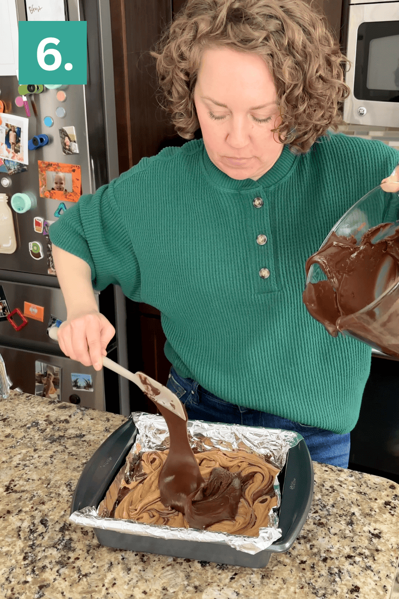 A woman in a green sweater pours chocolate batter from a bowl into a foil-lined square baking pan on a granite countertop, following a recipe step labeled 6. Kitchen appliances and photos are visible in the background.