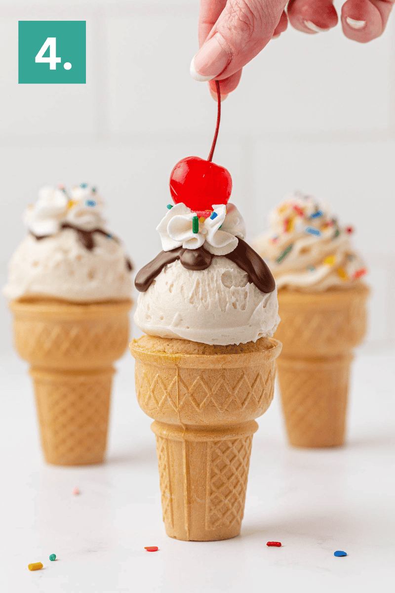 A hand places a cherry on top of an ice cream cone with vanilla ice cream, whipped cream, chocolate syrup, and sprinkles. Two more decorated ice cream cones stand in the background. A green square with the number 4 is in the upper left corner.