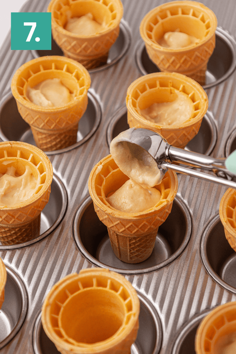 Ice cream cones placed upright in a muffin pan are being filled with batter using a scoop. A green square with the number 7 appears in the corner.