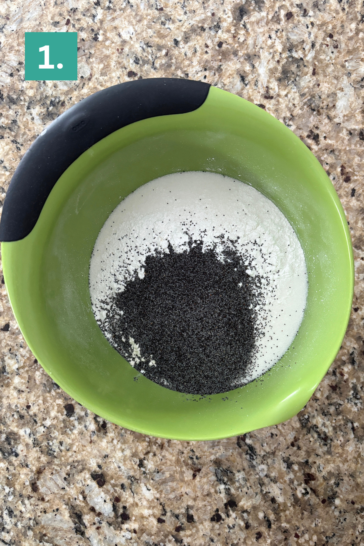 A green mixing bowl with flour and poppy seeds inside sits on a granite countertop. A green square with the number 1 is in the top left corner.
