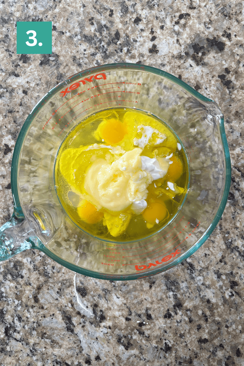 A glass Pyrex measuring cup containing eggs, mayonnaise, and what appears to be cottage cheese, sitting on a speckled granite countertop. A green box with the number 3 is in the top left corner.