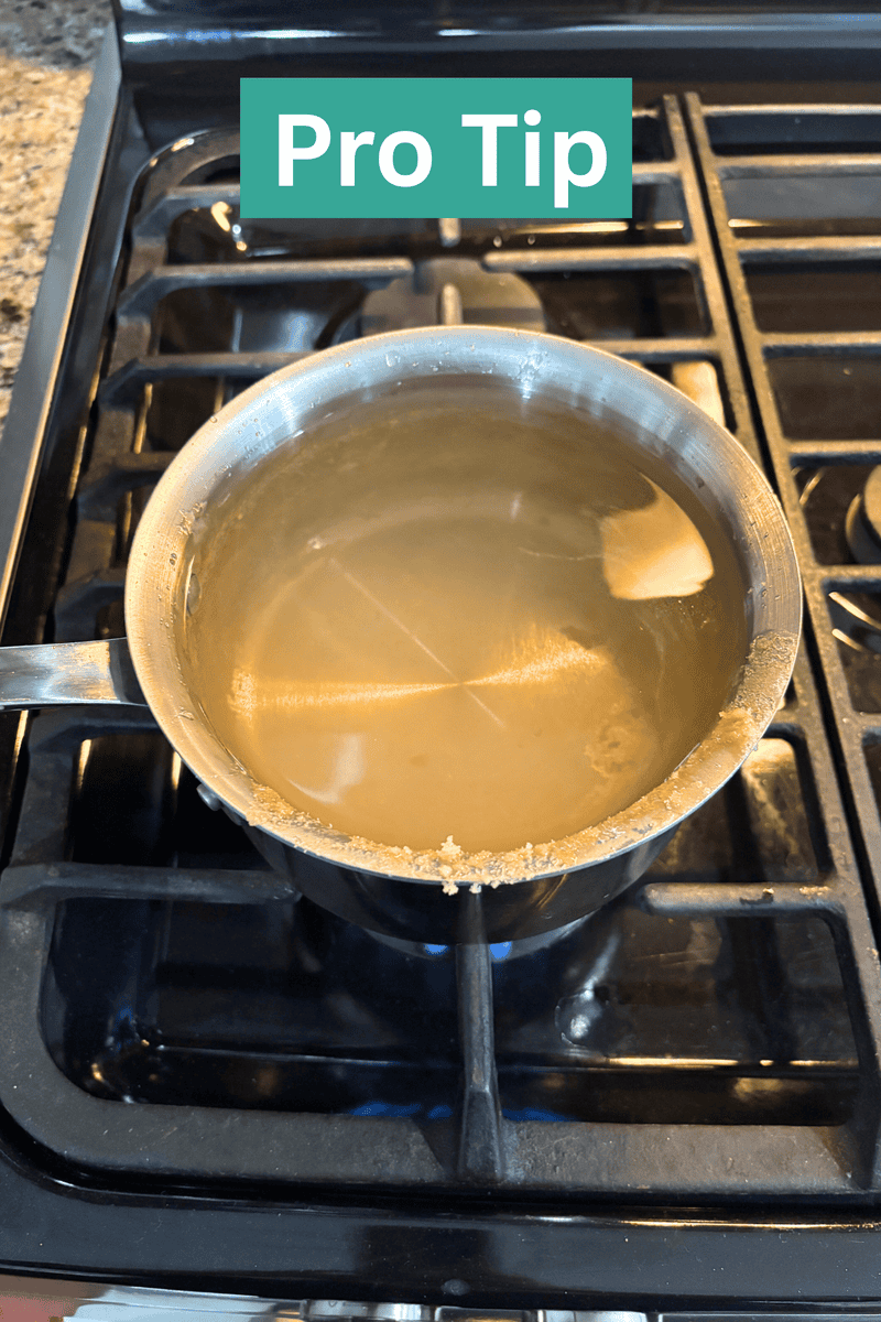 A metal pot with cloudy boiling water sits on a gas stove. Residue clings to the rim. At the top of the image, text reads Pro Tip in bold white letters on a green background.