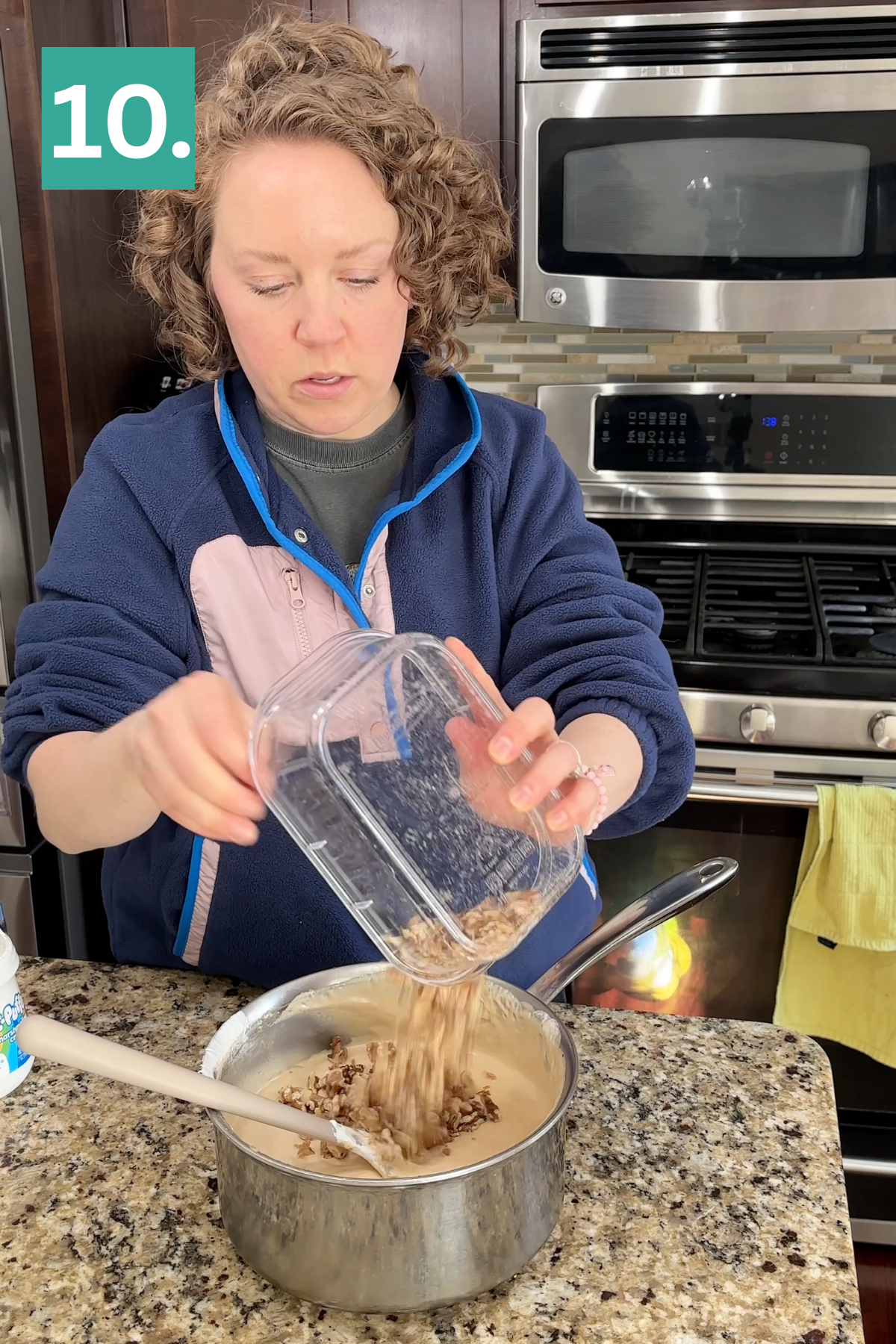 A woman pours chopped nuts from a container into a saucepan on a granite kitchen counter, with a stove and microwave in the background. A green box with the number “10.” appears in the top left corner.