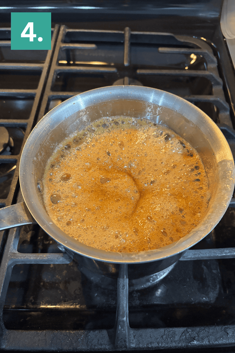 A saucepan filled with bubbling caramel sits on a stove burner. In the top left corner, a green box with the number 4 marks the step in a recipe.
