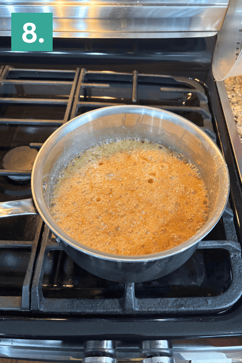 A stainless steel pot with bubbling caramel sauce cooks on a gas stove. A teal box in the upper left corner displays the number 8.