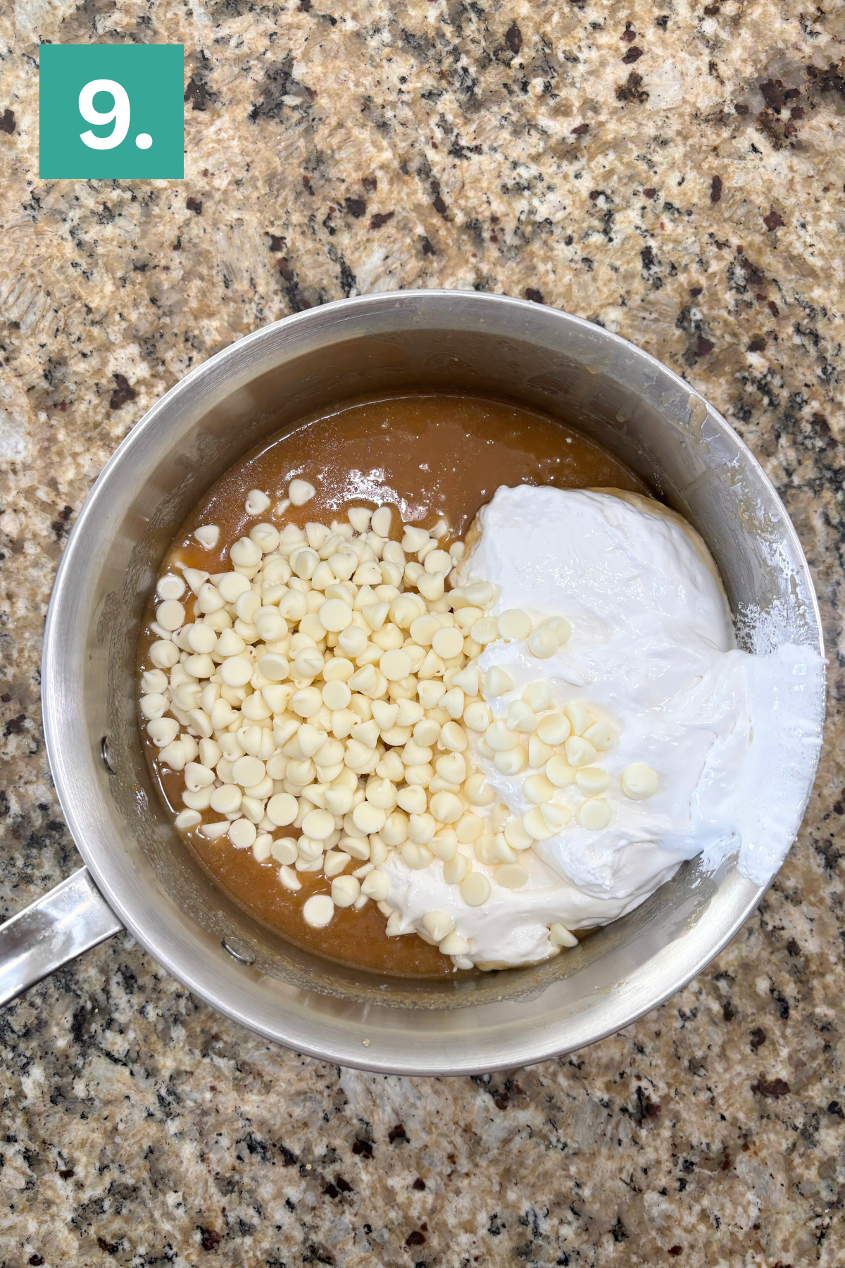 A metal saucepan on a speckled countertop contains a brown mixture, white chocolate chips, and a dollop of white marshmallow fluff. A green square with the number 9 is in the upper left corner.