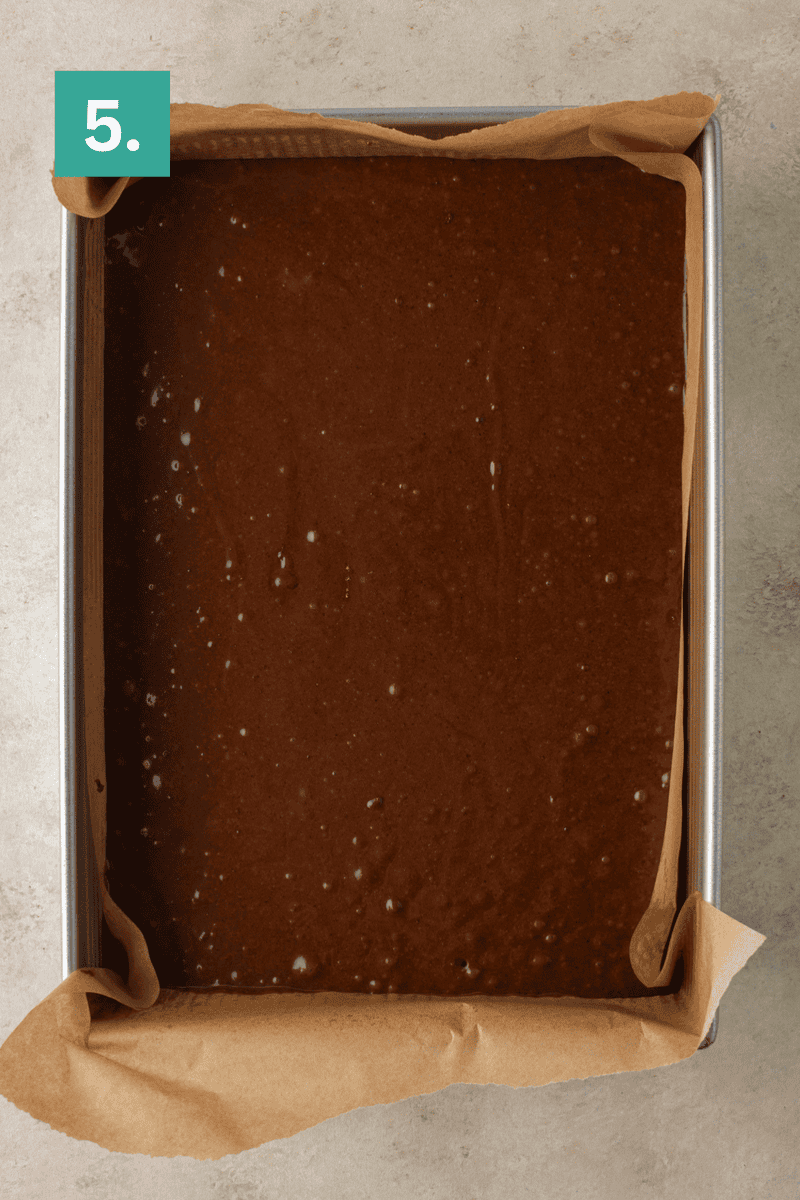 Rectangular baking pan lined with parchment paper, filled with chocolate batter. A green box with the number 5 is in the top left corner of the image.