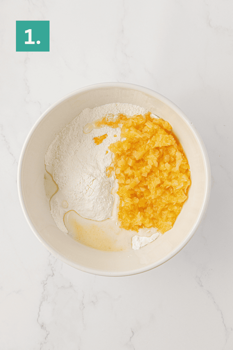 A mixing bowl with flour, chopped pineapple, and a bit of liquid, ready to be mixed; a green box in the top left corner displays the number 1.