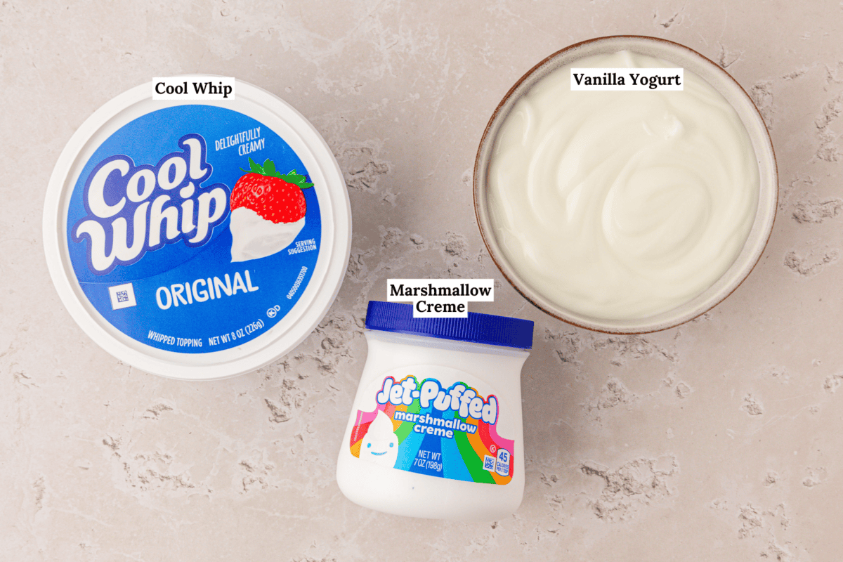 A bowl of vanilla yogurt, a tub of Cool Whip, and a jar of Jet-Puffed marshmallow creme on a light countertop, each labeled accordingly.