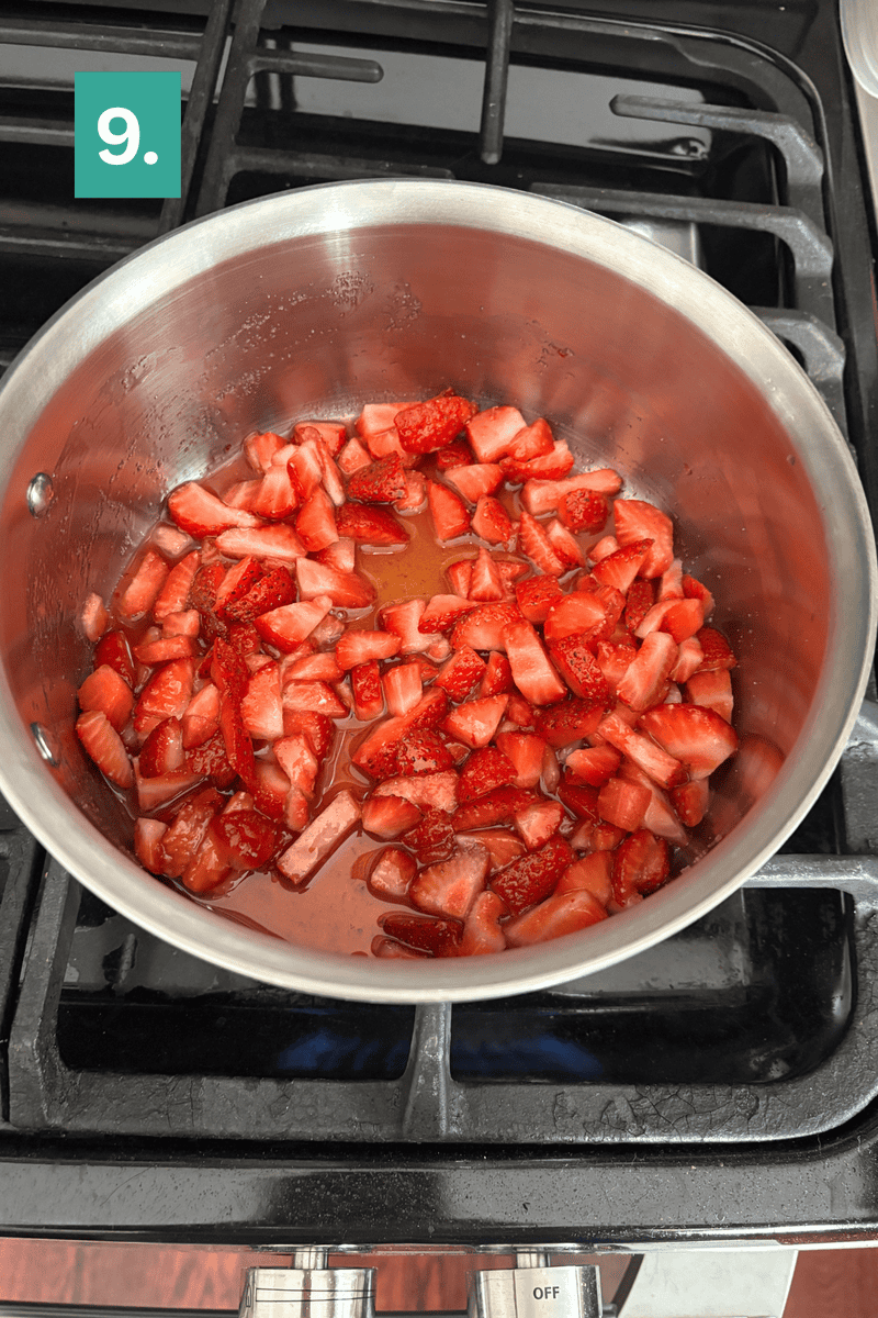 A stainless steel pot with chopped strawberries and liquid simmering on a stovetop. A green box with the number 9 appears in the top left corner.