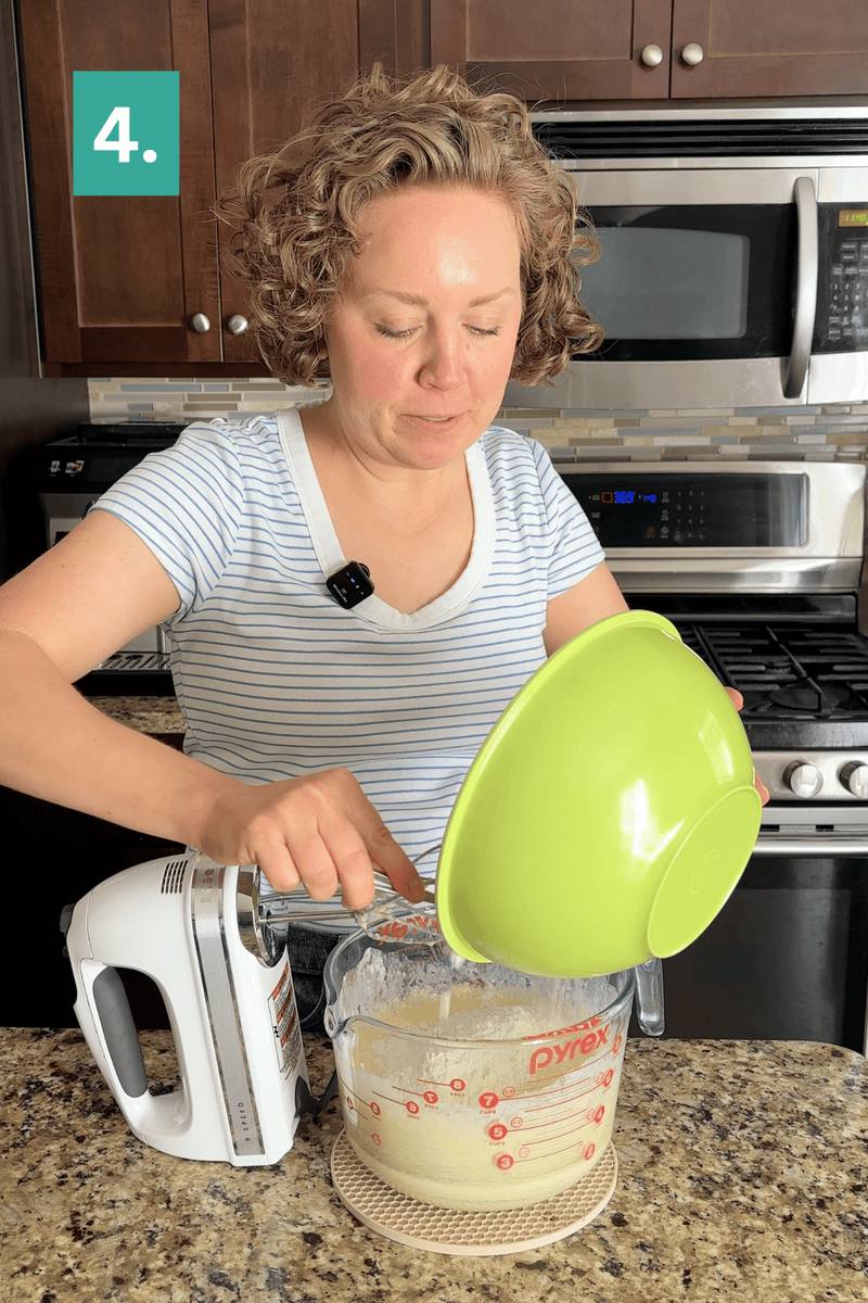 A person in a striped shirt pours ingredients from a green bowl into a glass measuring cup, holding a hand mixer, in a kitchen. A green box with the number 4 is in the top left corner.