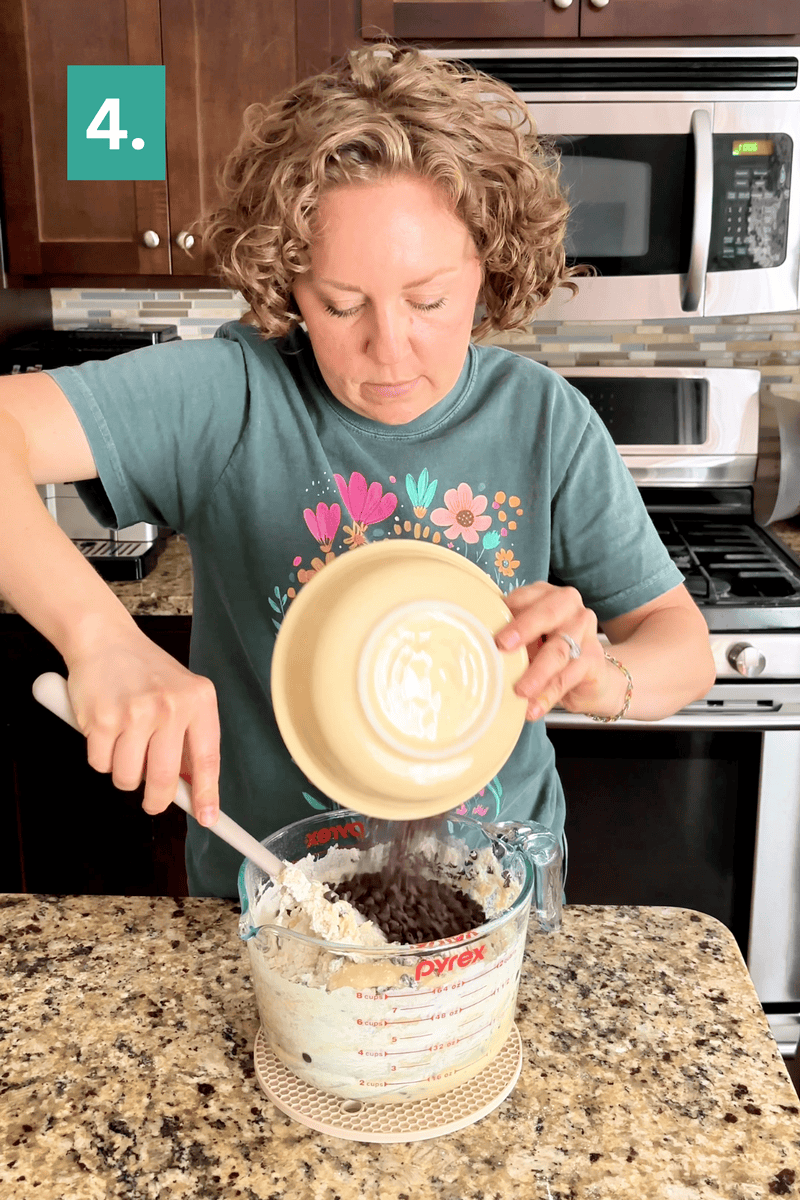 A woman stands in a kitchen pouring ingredients from a yellow bowl into a large Pyrex measuring cup, mixing batter with a spatula. A green square with the number 4 is in the top left corner.