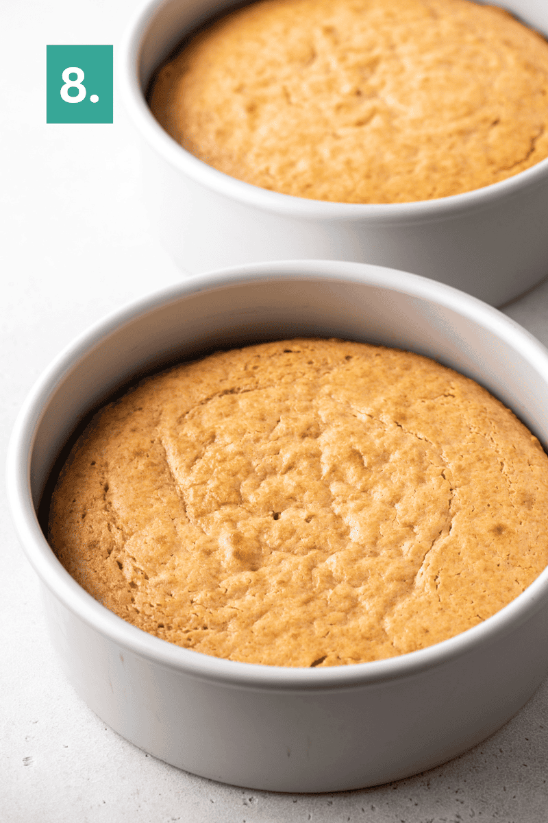 Two round cakes in white pans rest on a light surface. The cakes are golden brown and evenly risen. A green box with the number 8. is in the upper left corner.