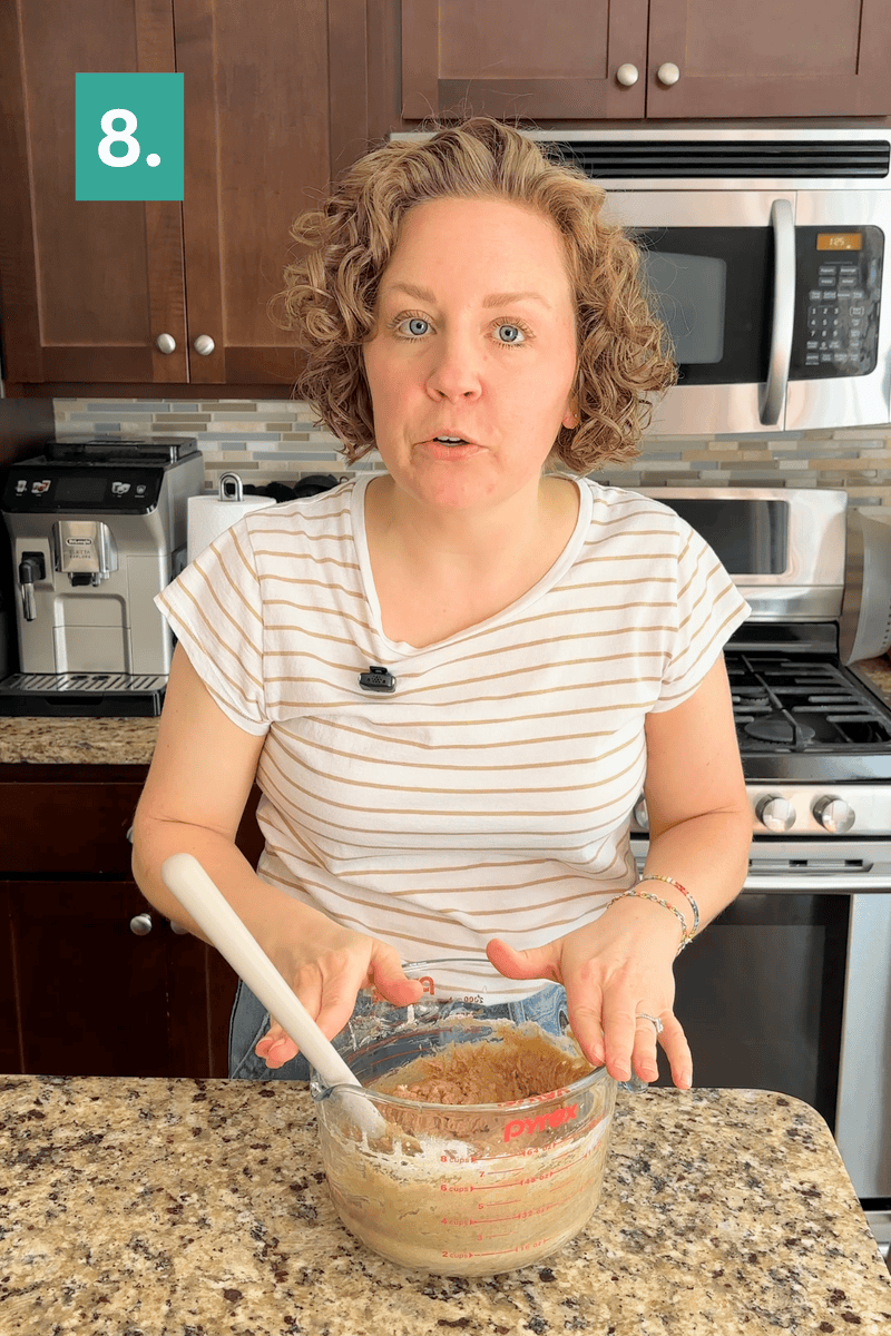 A woman in a striped shirt mixes ingredients in a glass bowl on a kitchen counter. A step 8 label is in the top left corner. Stainless steel appliances and wooden cabinets are visible in the background.