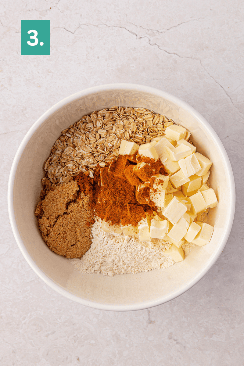 A white bowl holds oats, cubed butter, flour, brown sugar, and ground cinnamon, arranged in sections on a light countertop. A green box with a white number 3 is in the top left corner.