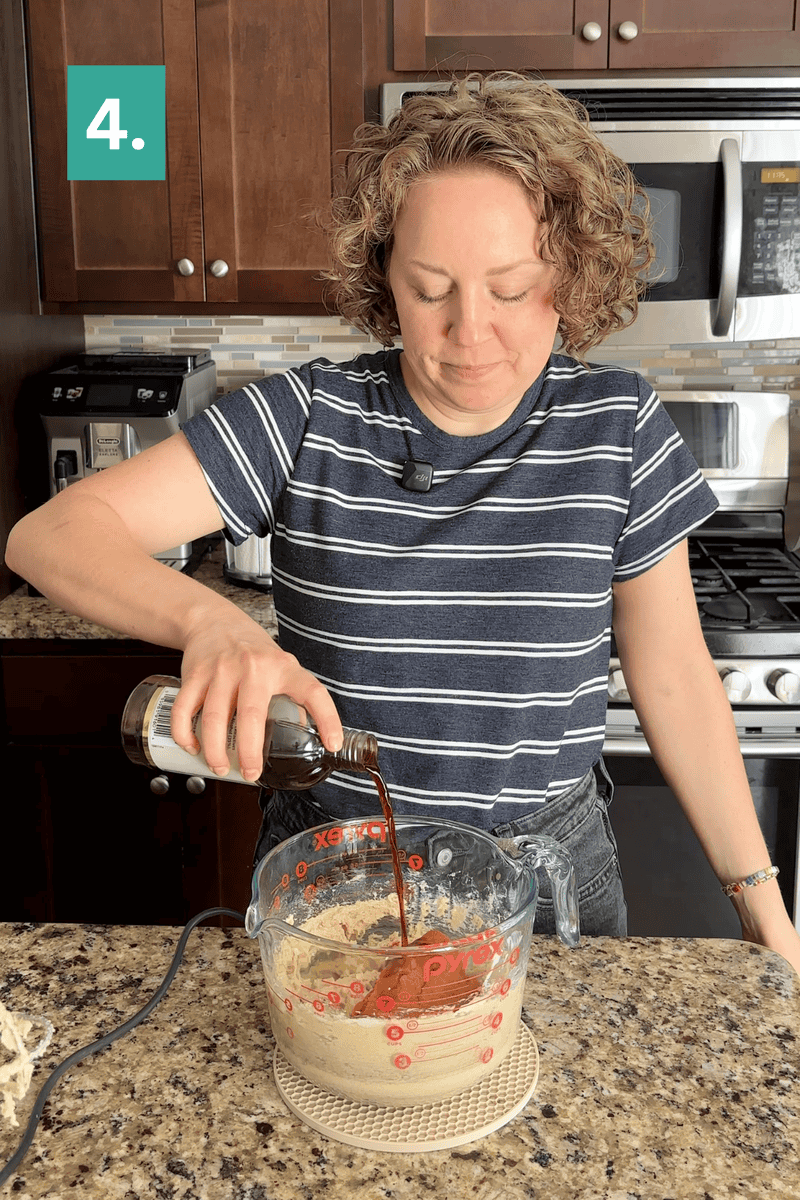 A person in a striped shirt pours liquid from a bottle into a large measuring cup with ingredients, standing in a kitchen with brown cabinets and appliances. A green box with the number 4 is in the top left corner.