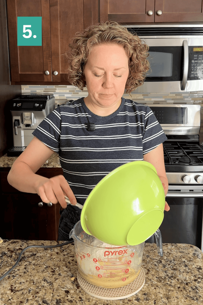 A person pours ingredients from a green bowl into a glass Pyrex measuring cup in a kitchen. A green step 5 label is in the top left corner.